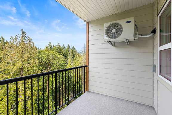 A balcony with a black railing and a window overlooking a forest.