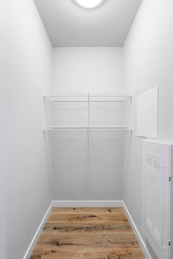 A white closet with a wooden floor and a white door.