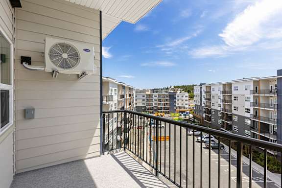 A balcony with a fan and a view of apartment buildings.