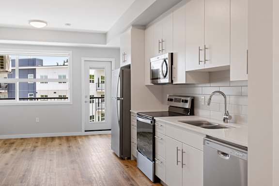 A kitchen with white cabinets and a stainless steel dishwasher.