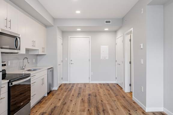 A kitchen with white cabinets and a wooden floor.
