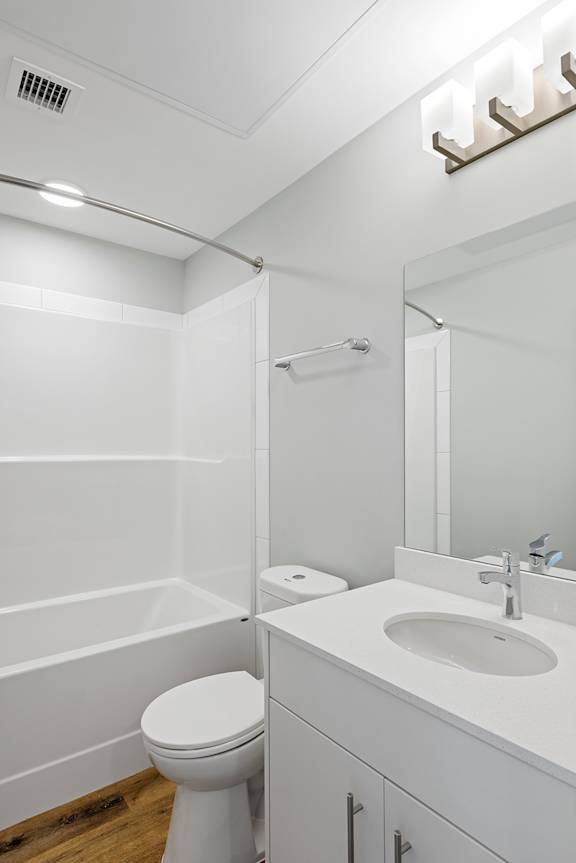 A white bathroom with a toilet, sink, and mirror.