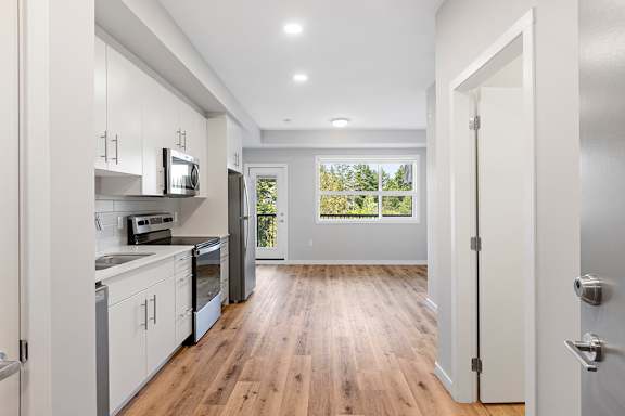 A kitchen with white cabinets and a window overlooking trees.