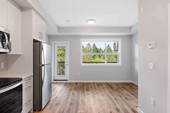 A kitchen with a refrigerator, oven, and microwave.