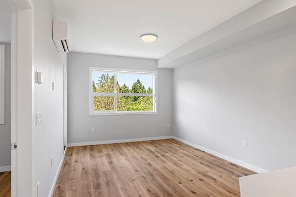 A room with a window overlooking a tree-filled landscape.
