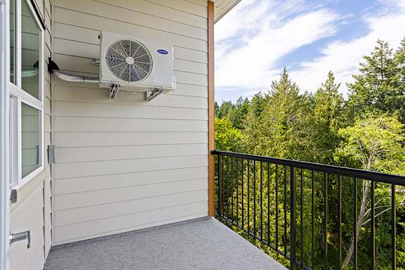 A balcony with a fan and trees in the background.