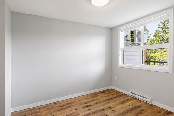 A room with a window and a wooden floor.