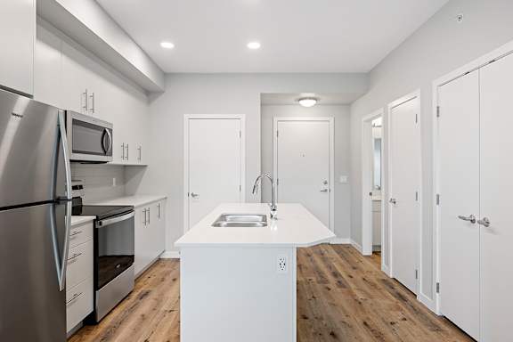 A modern kitchen with a stainless steel refrigerator and white cabinets.