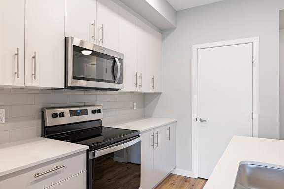 A modern kitchen with white cabinets and stainless steel appliances.
