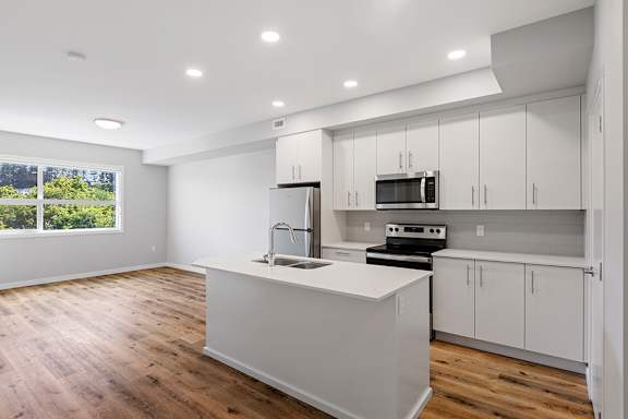 A modern kitchen with white cabinets and wooden floors.
