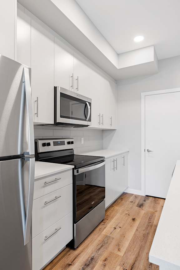 A modern kitchen with a refrigerator, oven, and microwave.