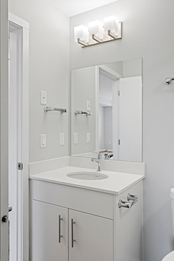 A white bathroom with a sink, mirror, and cabinets.