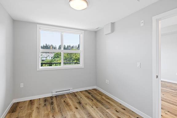 A room with a window showing a view of a house and trees.