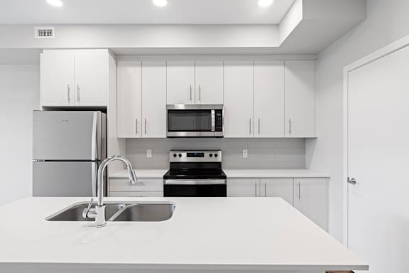 A modern kitchen with white cabinets and stainless steel appliances.