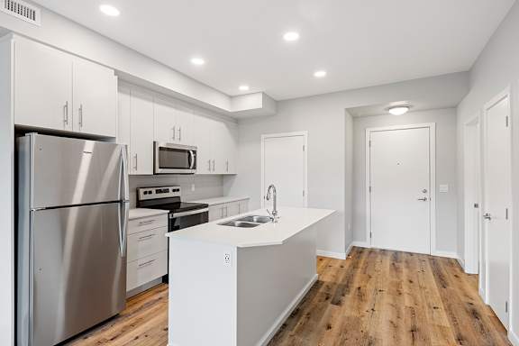 A modern kitchen with wooden floors and stainless steel appliances.