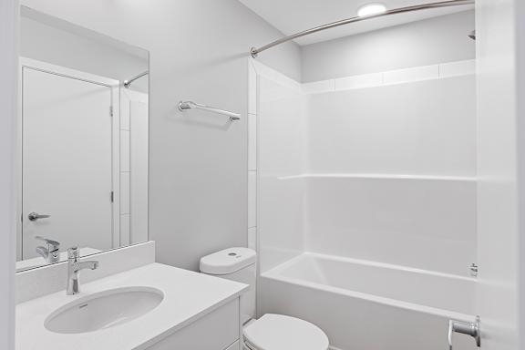 A white bathroom with a toilet, sink, and bathtub.
