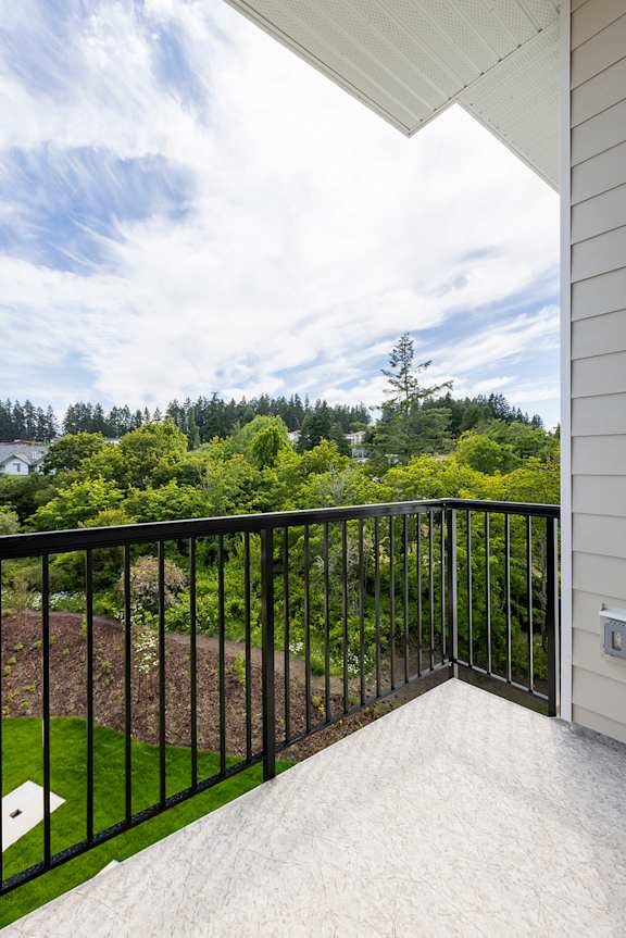 A balcony with a black railing overlooking a green landscape.