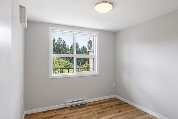 A room with a window overlooking a forest.