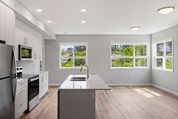 A modern kitchen with a refrigerator, oven, and sink.