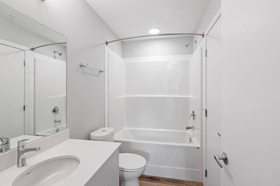 A white bathroom with a toilet, sink, and shower.