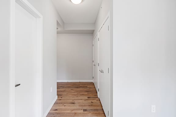 A long white hallway with wood floors and white walls.