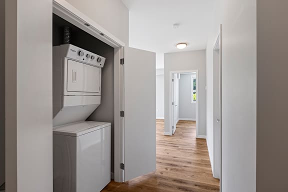 A white oven and dishwasher are built into a wall in a narrow hallway.