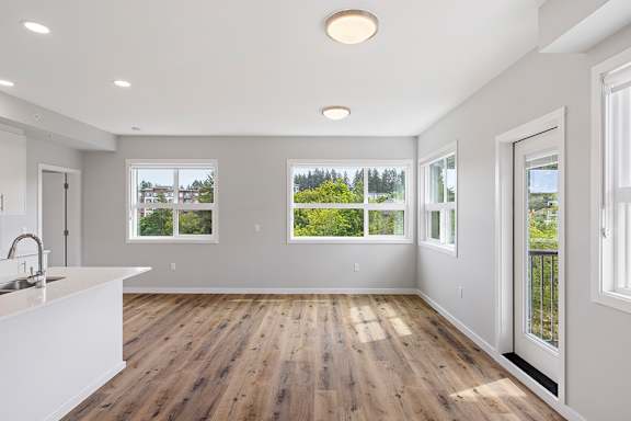 A spacious kitchen with wooden floors and white walls.