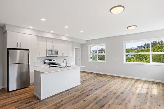 A modern kitchen with a wooden floor and white appliances.