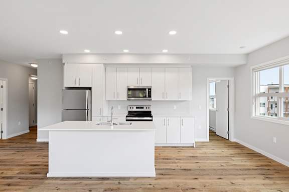 A modern kitchen with white cabinets and appliances.