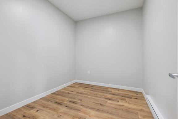A room with wooden flooring and white walls.