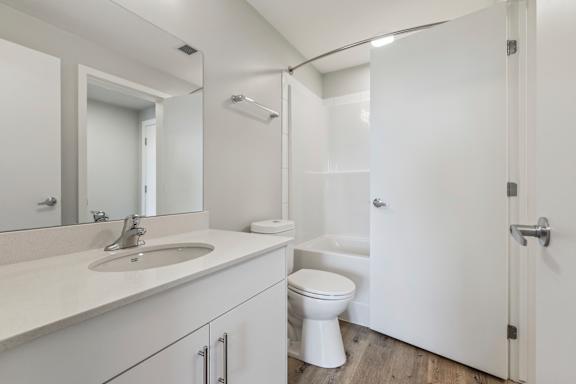 A white bathroom with a sink, toilet, and shower.