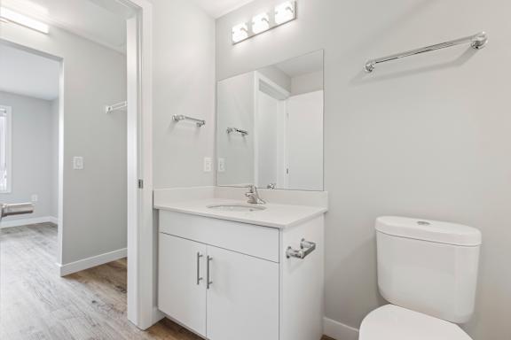 A white bathroom with a toilet, sink, and mirror.