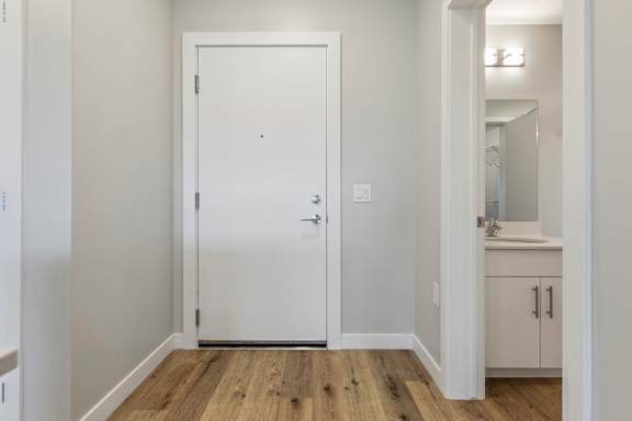 A white door is in a room with wooden floors.
