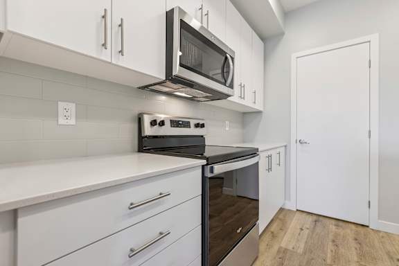 A modern kitchen with white cabinets and stainless steel appliances.