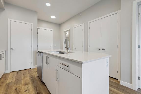 A white kitchen with wooden floors and white cabinets.