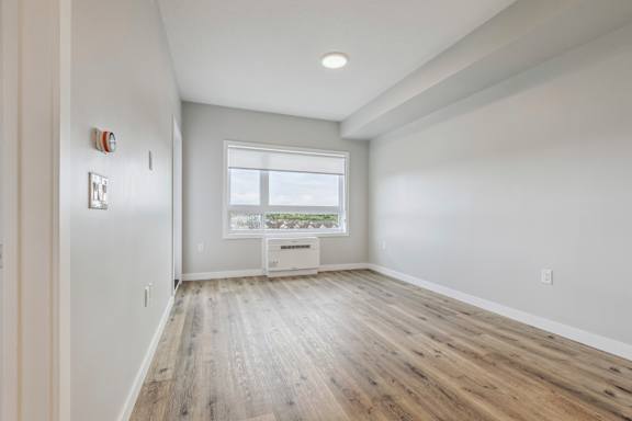 A room with a window and a radiator on the floor.