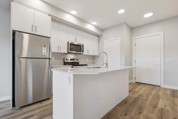 A modern kitchen with white cabinets and a stainless steel refrigerator.
