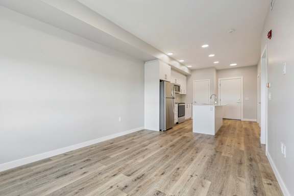 A spacious kitchen with white cabinets and a refrigerator.