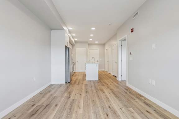 A long hallway with wood floors and white walls.