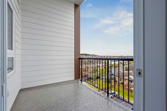 A balcony with a black railing and a view of a street with cars.