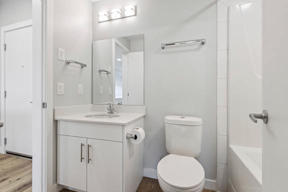 A white bathroom with a toilet, sink, and mirror.