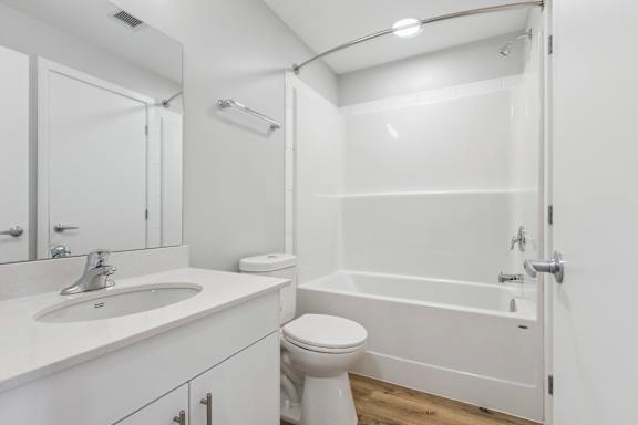 A white bathroom with a toilet, sink, and bathtub.