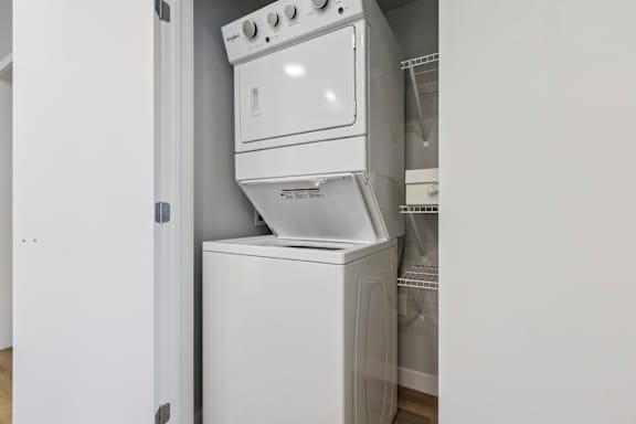 A white dishwasher is stacked on top of a white oven.