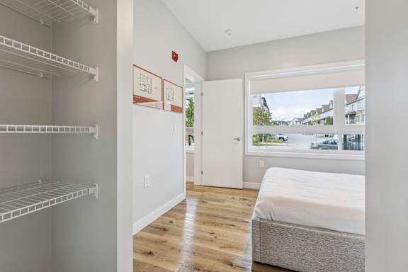 A white bedroom with a bed and a window overlooking a street.