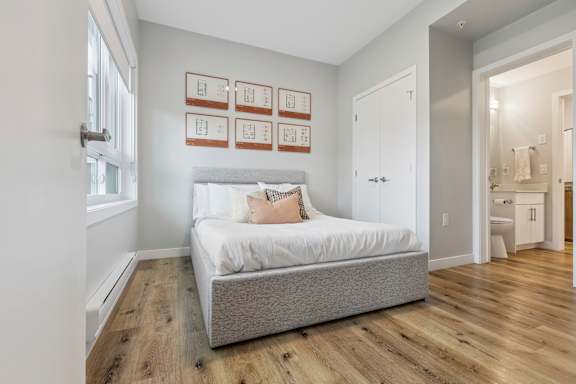 A bedroom with a bed, wooden floors, and pictures on the wall.