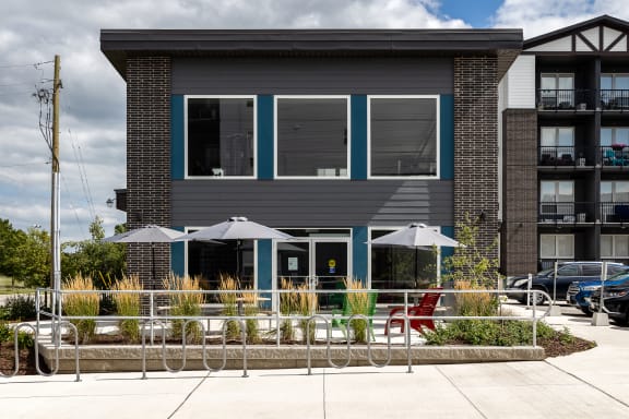 a building with blue windows and a patio with chairs and umbrellas