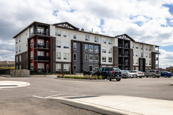 an apartment building with cars parked in a parking lot
