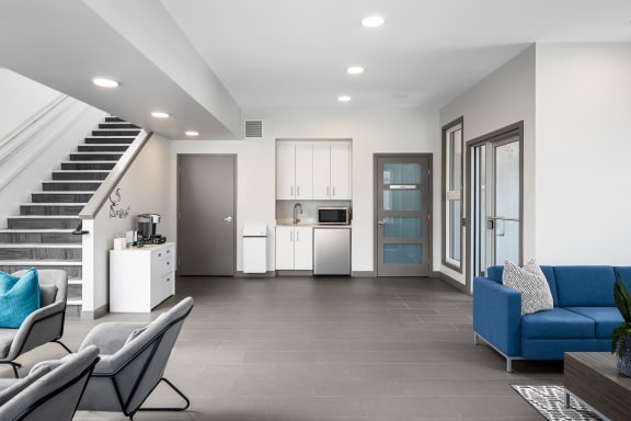 a living room with couches and chairs and a kitchen and stairs