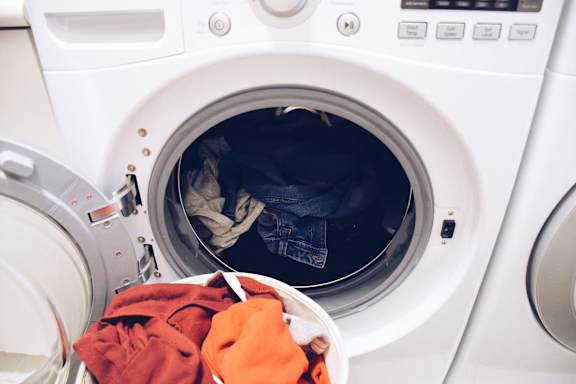 A washing machine with clothes inside and a red towel on the door.