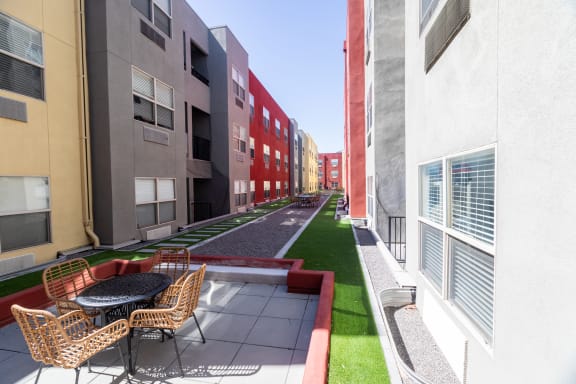a rendering of a courtyard between two buildings with chairs and a table at ParcOne60, Reno, 89501